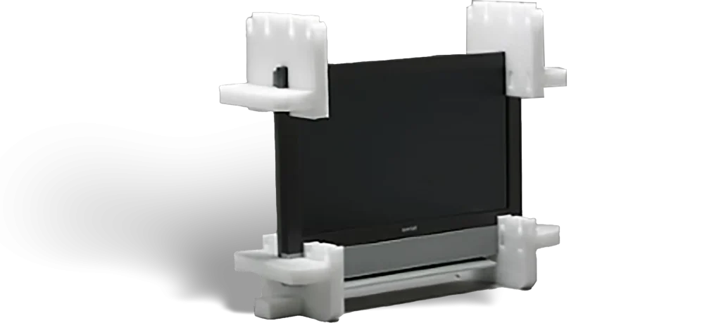 Televisor protegido con esquineras y base de embalaje en espuma para transporte seguro.
