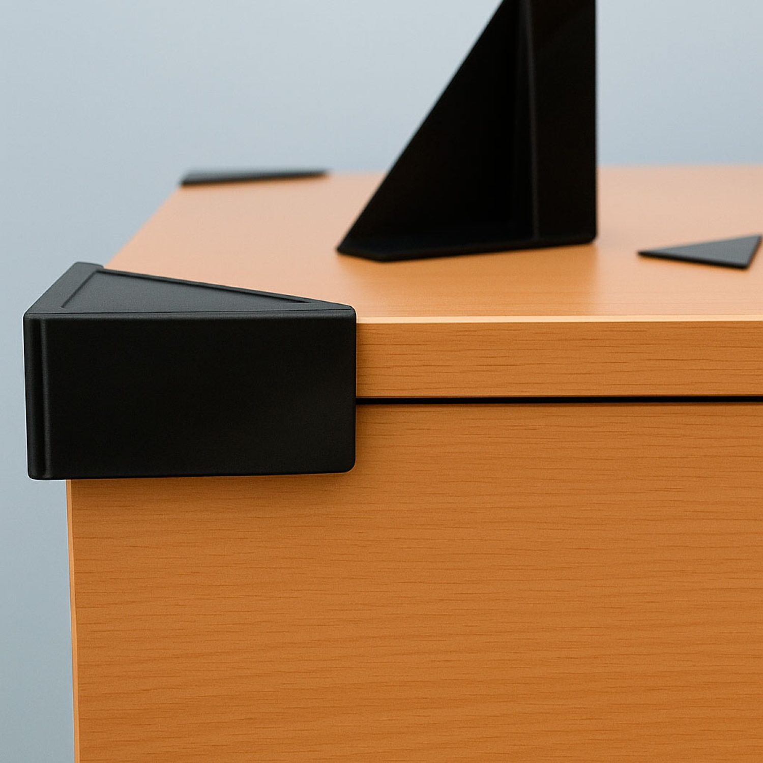 Esquinera de plástico negro instalada en la esquina de un mueble, diseñada para proteger cantos y superficies frente a golpes y roces.