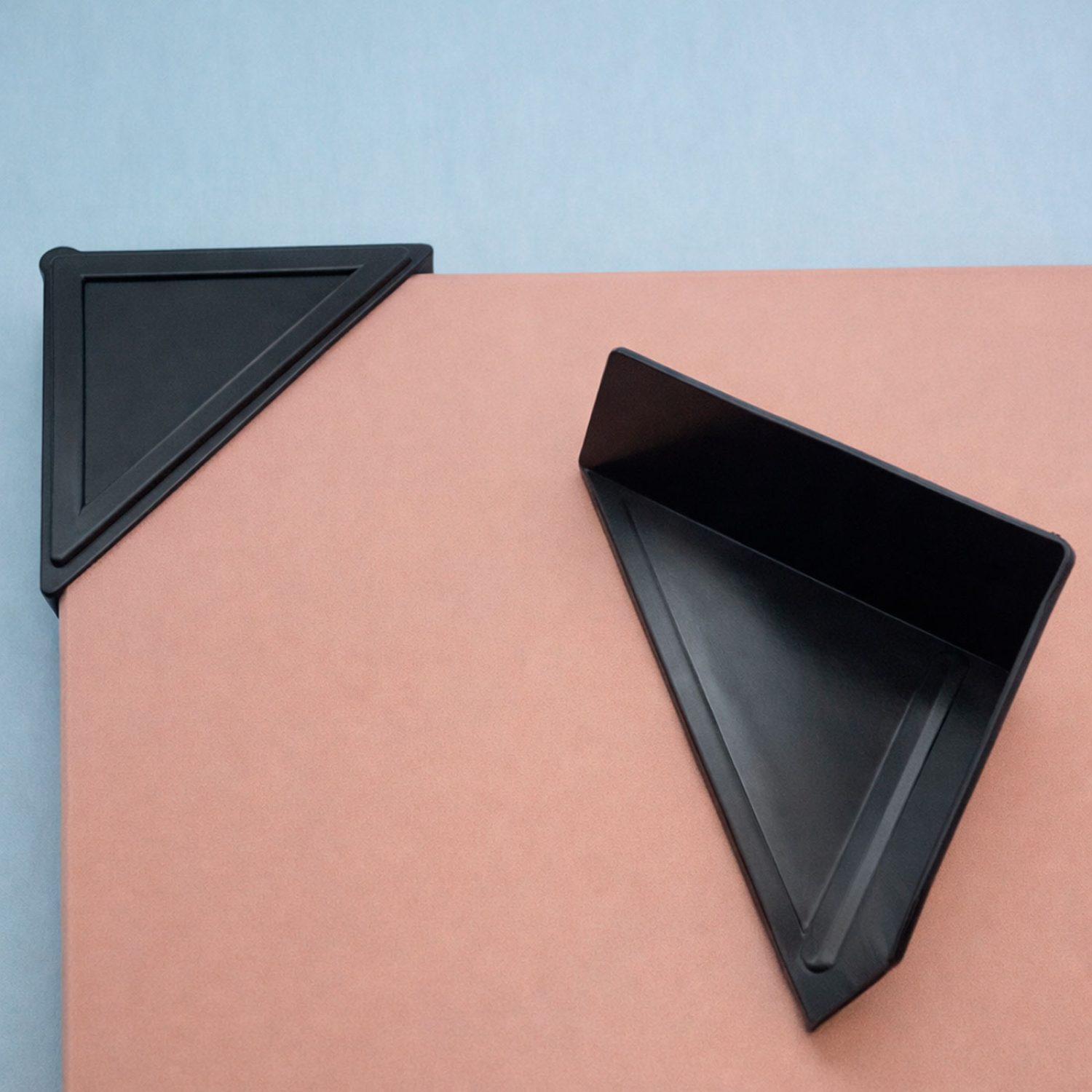 Esquineras de plástico negro en forma triangular, diseñadas para reforzar y proteger las esquinas de muebles y embalajes durante el transporte.